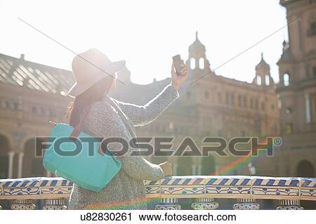 Stock Image - Mature female tourist photographing Plaza de Espana, Seville, Spain. Fotosearch