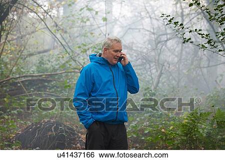Mature male runner chatting on smartphone in misty forest View Large Photo Image Stock Photograph - Mature male runner chatting on smartphone in misty forest. Fotosearch