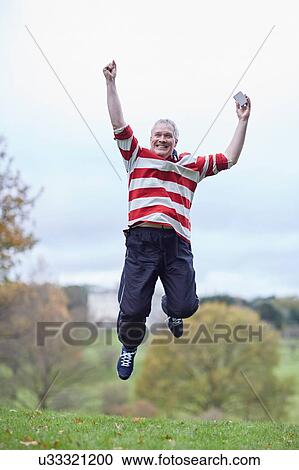 Mature male runner jumping in celebration in field View Large Photo Image Stock Image - Mature male runner jumping in celebration in field. Fotosearch