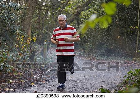 Mature male runner running through on forest track View Large Photo Image Stock Photo - Mature male runner running through on forest track. Fotosearch
