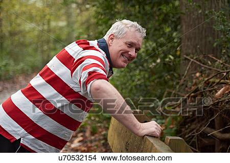 Picture - Mature man doing push ups against park bench in forest. Fotosearch