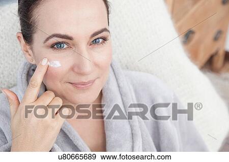 Stock Photo - Mature woman applying moisturiser to face. Fotosearch