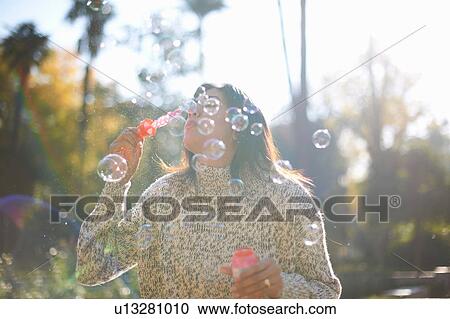 Stock Image - Mature woman blowing bubbles, Seville, Spain. Fotosearch