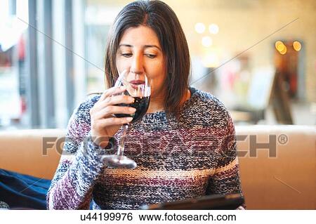 Mature woman drinking red and reading digital tablet in wine bar View Large Photo Image Stock Photograph - Mature woman drinking red and reading digital tablet in wine bar. Fotosearch