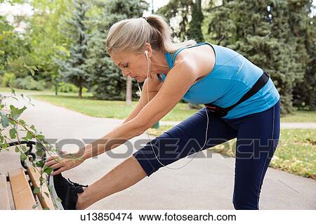 Mature woman training and touching toes on park bench View Large Photo Image Picture - Mature woman training and touching toes on park bench. Fotosearch