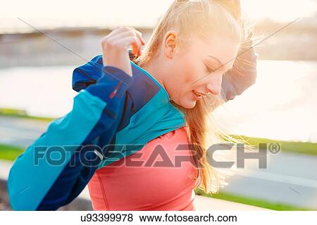 Mid adult female runner removing tracksuit top at city riverside View Large Photo Image Stock Photo - Mid adult female runner removing tracksuit top at city riverside. Fotosearch