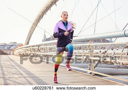 Mid adult female runner running at speed on city footbridge View Large Photo Image Stock Image - Mid adult female runner running at speed on city footbridge. Fotosearch