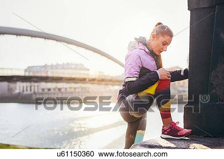 Mid adult female runner warming up at city riverside View Large Photo Image Stock Image - Mid adult female runner warming up at city riverside. Fotosearch