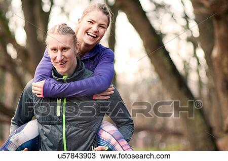 Stock Image - Mid adult man giving young smiling woman piggyback. Fotosearch