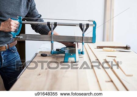 Mid adult man sawing wood View Large Photo Image Stock Photography - Mid adult man sawing wood. Fotosearch
