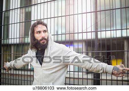 Mid adult man standing against fence, looking away View Large Photo Image Stock Image - Mid adult man standing against fence, looking away. Fotosearch