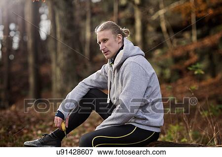 Mid adult man wearing sports clothes holding banana looking away View Large Photo Image Stock Photo - Mid adult man wearing sports clothes holding banana looking away. Fotosearch