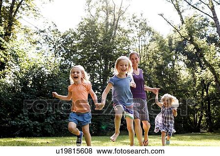Mid adult woman and three young daughters running in park View Large Photo Image Stock Photo - Mid adult woman and three young daughters running in park. Fotosearch