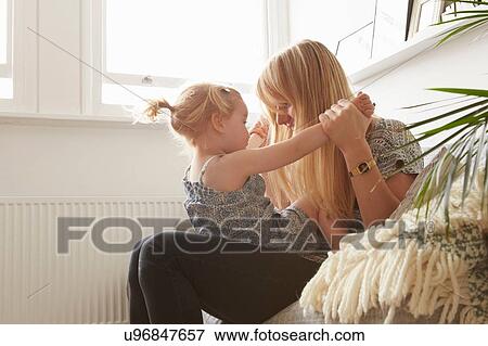 Stock Photo - Mid adult woman and toddler daughter playing on sofa. Fotosearch