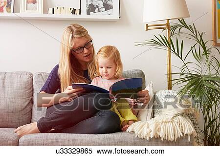 Mid adult woman and toddler daughter reading on sofa View Large Photo Image Stock Photography - Mid adult woman and toddler daughter reading on sofa. Fotosearch