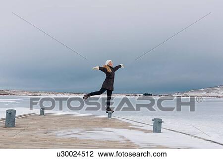 Mid adult woman by frozen lake standing on one leg on mooring post, arms open looking away View Large Photo Image Stock Image - Mid adult woman by frozen lake standing on one leg on mooring post, arms open looking away. Fotosearch