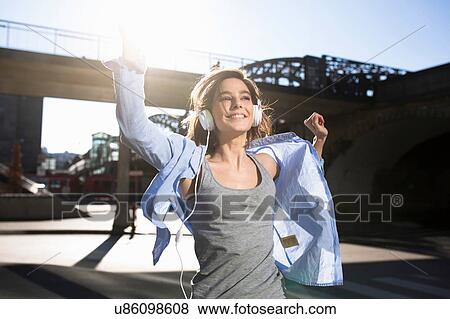 Mid adult woman dancing whilst listening to headphones in city View Large Photo Image Stock Photo - Mid adult woman dancing whilst listening to headphones in city. Fotosearch
