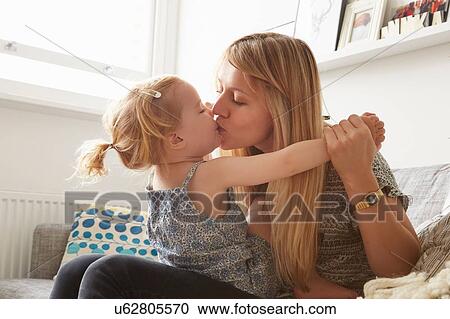 Mid adult woman kissing toddler daughter on sofa View Large Photo Image Stock Image - Mid adult woman kissing toddler daughter on sofa. Fotosearch