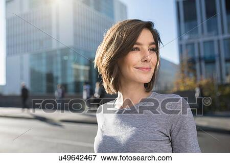 Mid adult woman looking over her shoulder on city road View Large Photo Image Stock Photo - Mid adult woman looking over her shoulder on city road. Fotosearch
