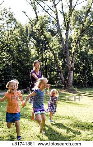 Mid adult woman running and holding hands with three daughters in park View Large Photo Image Stock Image - Mid adult woman running and holding hands with three daughters in park. Fotosearch