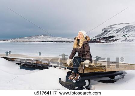 Mid adult woman sitting on pier by frozen lake looking away View Large Photo Image Stock Photo - Mid adult woman sitting on pier by frozen lake looking away. Fotosearch