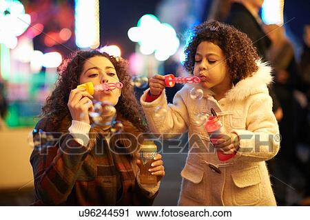 Mother and daughter blowing bubbles, at funfair View Large Photo Image Stock Image - Mother and daughter blowing bubbles, at funfair. Fotosearch