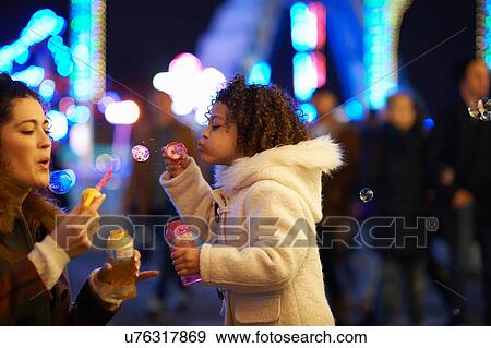 Mother and daughter blowing bubbles, at funfair View Large Photo Image Stock Photo - Mother and daughter blowing bubbles, at funfair. Fotosearch
