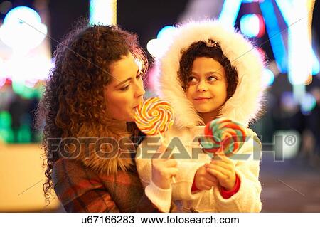 Stock Image - Mother and daughter enjoying lollipop. Fotosearch
