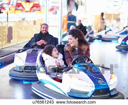 Stock Image - Mother and daughter in bumper car face to face smiling. Fotosearch