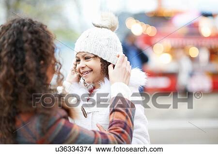 Mother putting knit hat on smiling daughter View Large Photo Image Picture - Mother putting knit hat on smiling daughter. Fotosearch