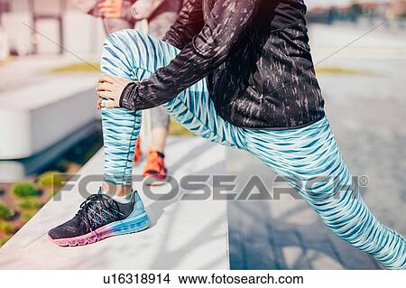 Picture - Neck down view of female runners warming up on city wall. Fotosearch