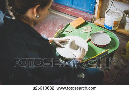 Over shoulder view of young woman sitting using pottery wheel View Large Photo Image Stock Image - Over shoulder view of young woman sitting using pottery wheel. Fotosearch