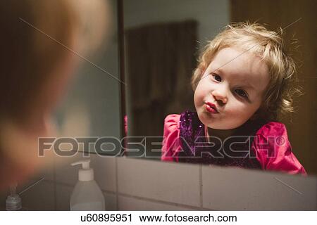 Over the shoulder view of girl wearing pink lipstick gazing at herself in mirror View Large Photo Image Stock Image - Over the shoulder view of girl wearing pink lipstick gazing at herself in mirror. Fotosearch