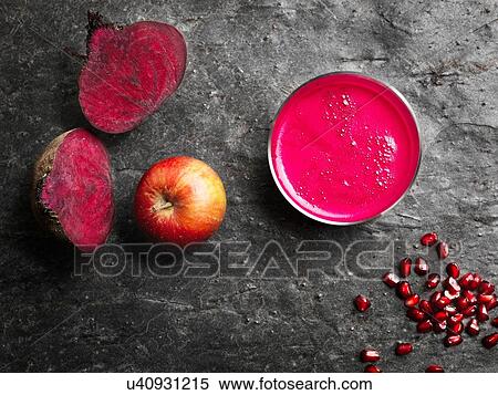 Stock Photography - Overhead view of pink raw juice and red fruit and vegetables on dark background. Fotosearch