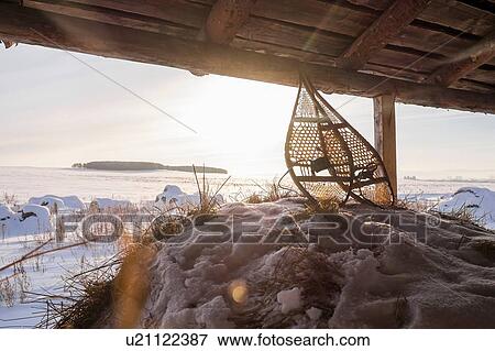 Stock Photo - Pair of snow shoes in barn with distant snow covered fields, Ural, Russia. Fotosearch