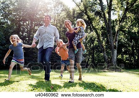 Parents and three young daughters running in park View Large Photo Image Stock Image - Parents and three young daughters running in park. Fotosearch