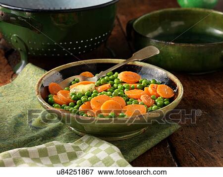 Stock Photo - Peas and sliced carrots in green serving dish. Fotosearch