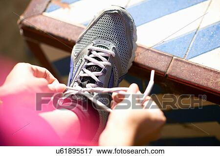 Stock Photo - Point of view shot of mature woman leg raised tying shoelace. Fotosearch