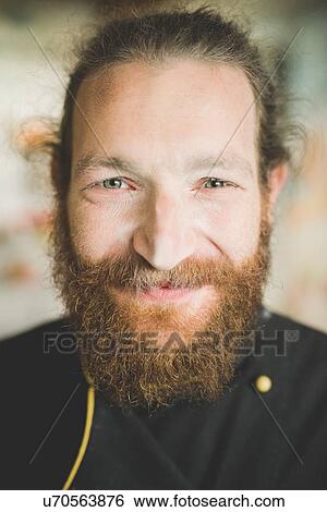 Stock Photograph - Portrait of bearded mid adult man looking at camera smiling. Fotosearch