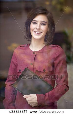 Portrait of businesswoman carrying digital tablet looking through window View Large Photo Image Stock Image - Portrait of businesswoman carrying digital tablet looking through window. Fotosearch