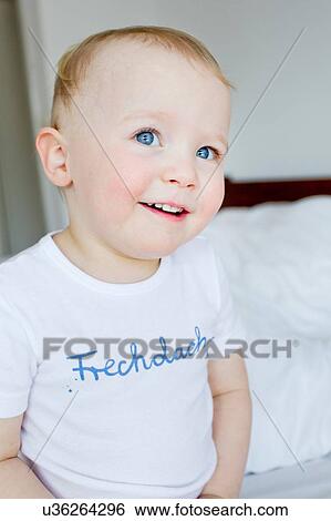 Portrait of cute blue eyed female toddler sitting on bed View Large Photo Image Stock Photograph - Portrait of cute blue eyed female toddler sitting on bed. Fotosearch