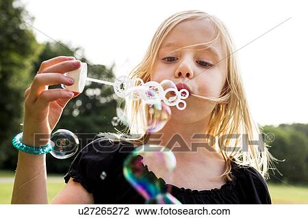 Portrait of cute girl blowing bubbles in park View Large Photo Image Stock Image - Portrait of cute girl blowing bubbles in park. Fotosearch
