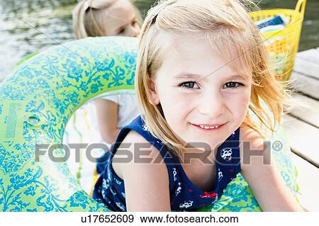 Portrait of cute girl playing with inflatable ring on pier at lake Starnberg, Bavaria, Germany View Large Photo Image Stock Photo - Portrait of cute girl playing with inflatable ring on pier at lake Starnberg, Bavaria, Germany. Fotosearch