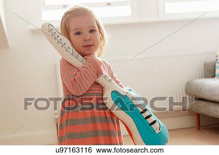Portrait of female toddler playing with toy guitar in living room View Large Photo Image Stock Photograph - Portrait of female toddler playing with toy guitar in living room. Fotosearch