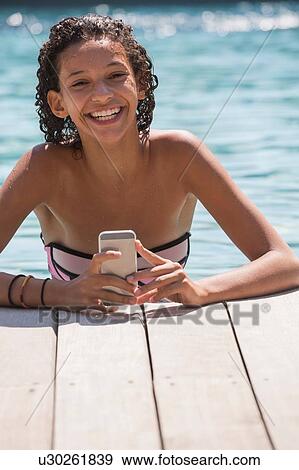 Portrait of girl in swimming pool using smartphone View Large Photo Image Stock Photo - Portrait of girl in swimming pool using smartphone. Fotosearch