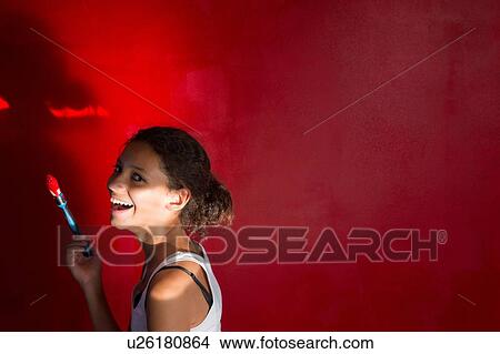 Picture - Portrait of girl laughing in front of red wall. Fotosearch