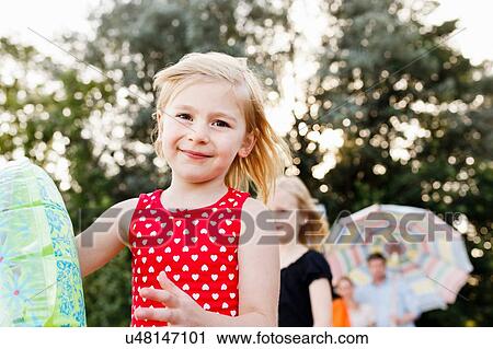 Stock Image - Portrait of girl playing with inflatable ring in park. Fotosearch