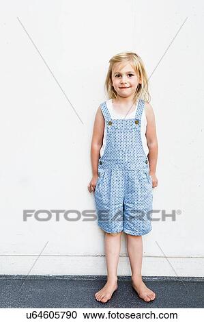Portrait of girl wearing dungarees in front of white wall View Large Photo Image Stock Image - Portrait of girl wearing dungarees in front of white wall. Fotosearch