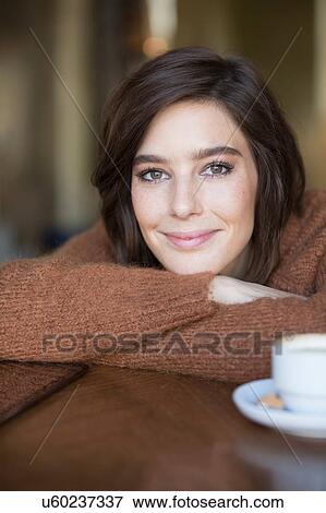 Stock Photo - Portrait of happy mid adult woman leaning forward at cafe table. Fotosearch