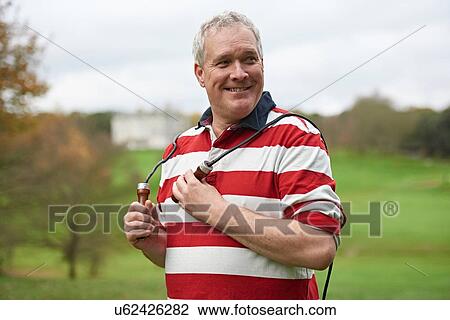 Stock Image - Portrait of mature man training in field with skipping rope. Fotosearch
